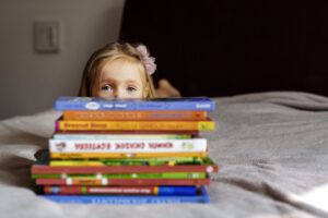 Child laying on bed with stack of books