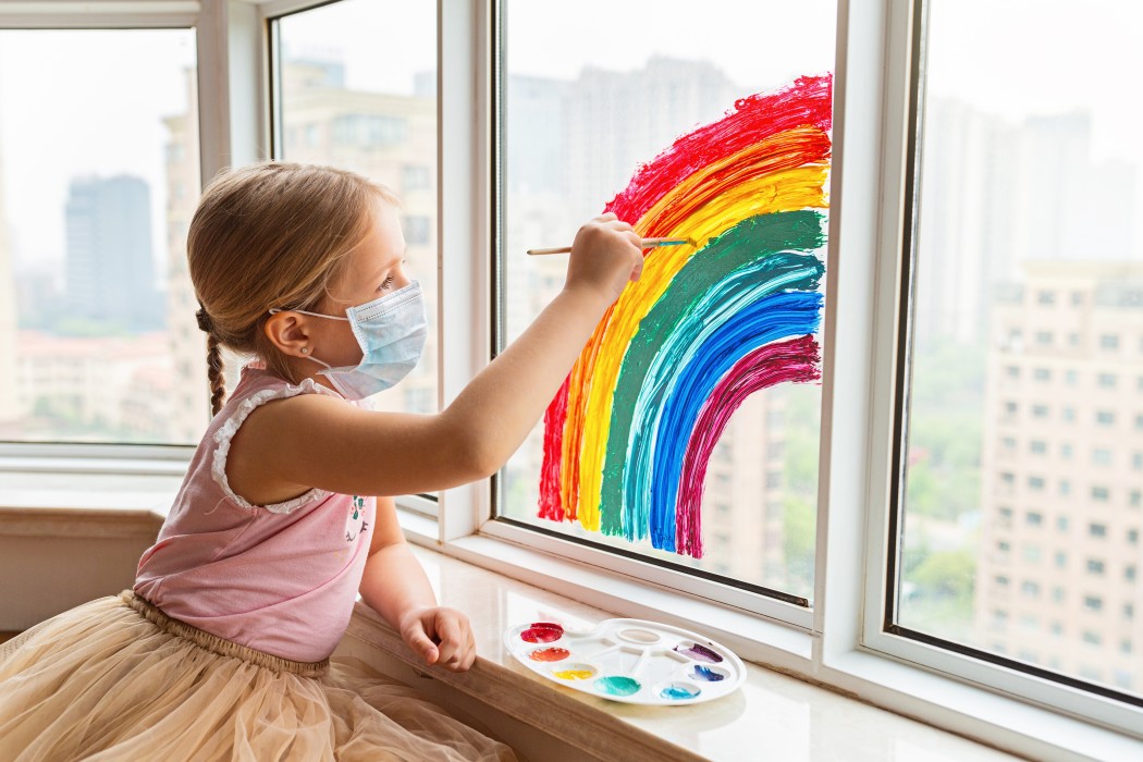 Child painting on window with mask