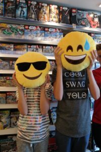 Kids holding emoji pillows in front of their face.