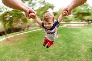 Kid swinging from adult arms