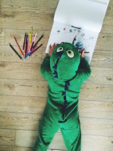 Child coloring in a dinosaur costume