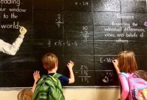 Kids writing math equations on a chalk board.