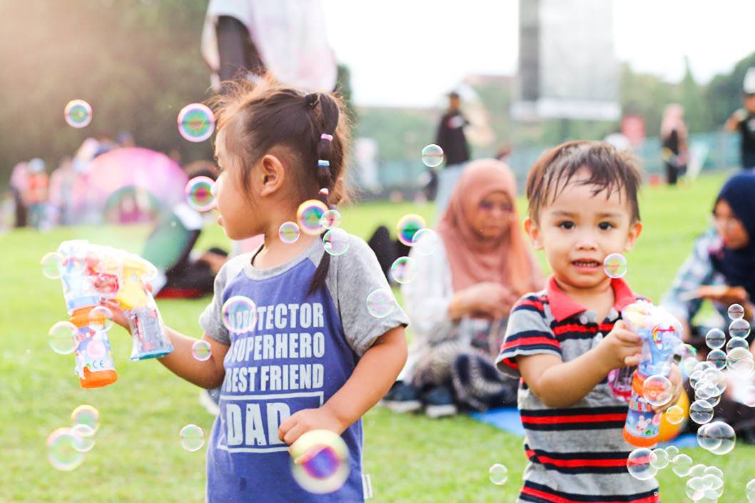 Kids blowing bubbles at a park.