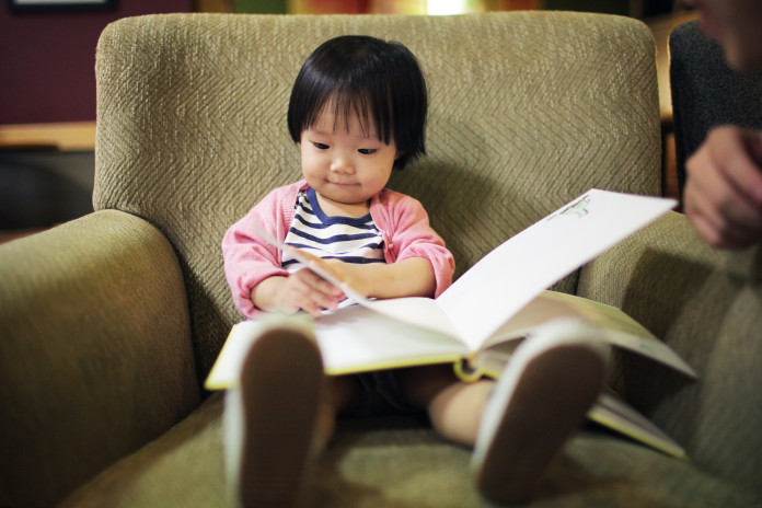 Little girl reading on a chair.