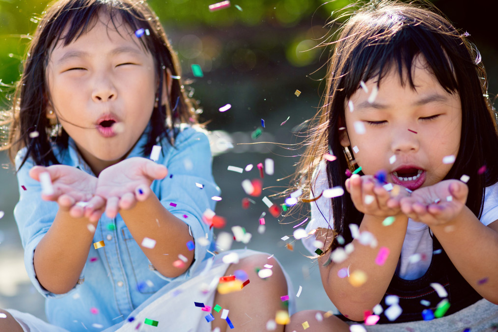 Little girls blowing party confetti.