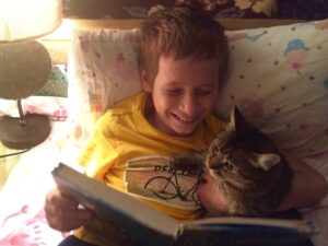 Kid reading with his cat.