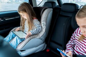 Kids playing games on a tablet during a family road trip.
