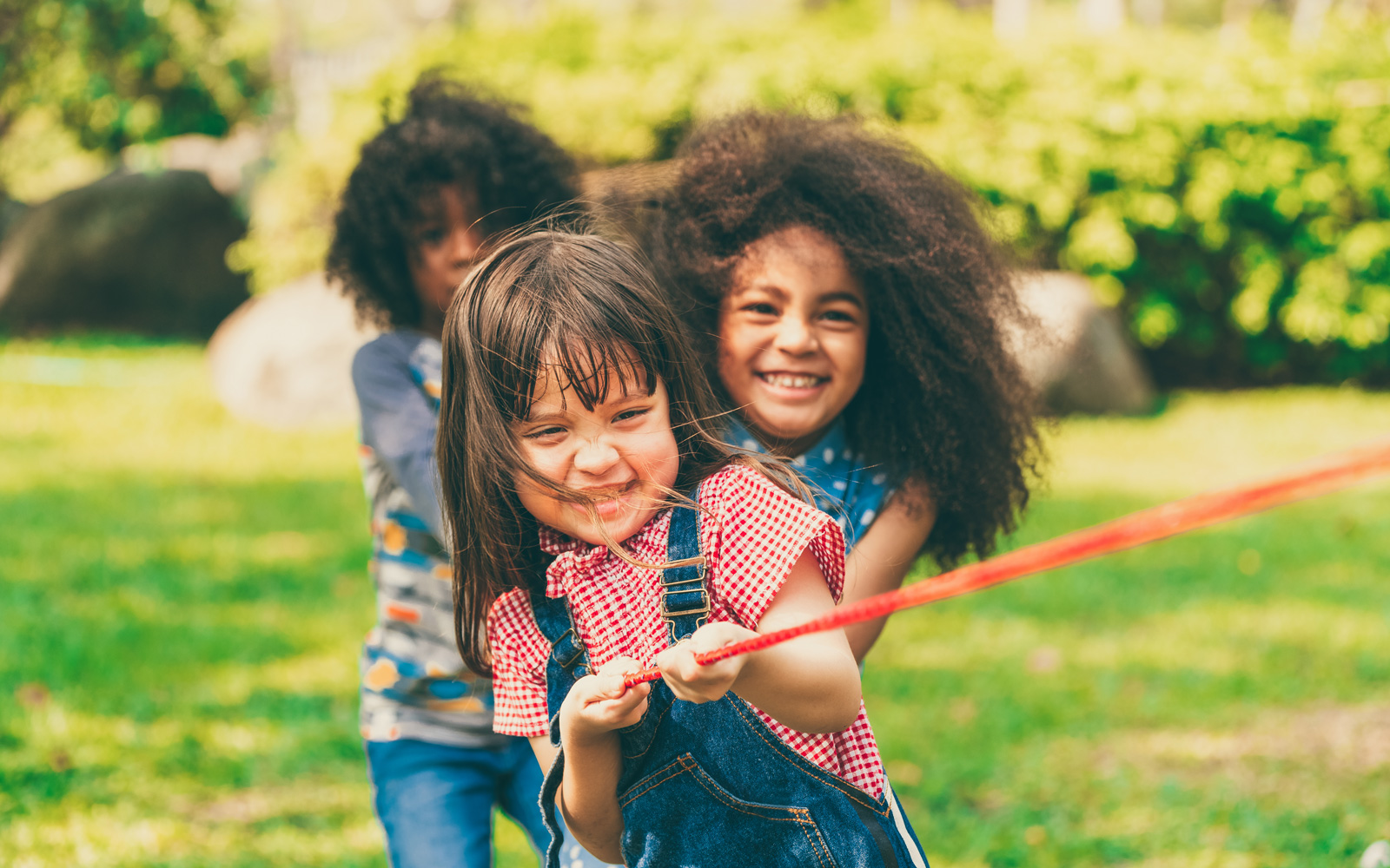 Kids play tug-of-war in a park