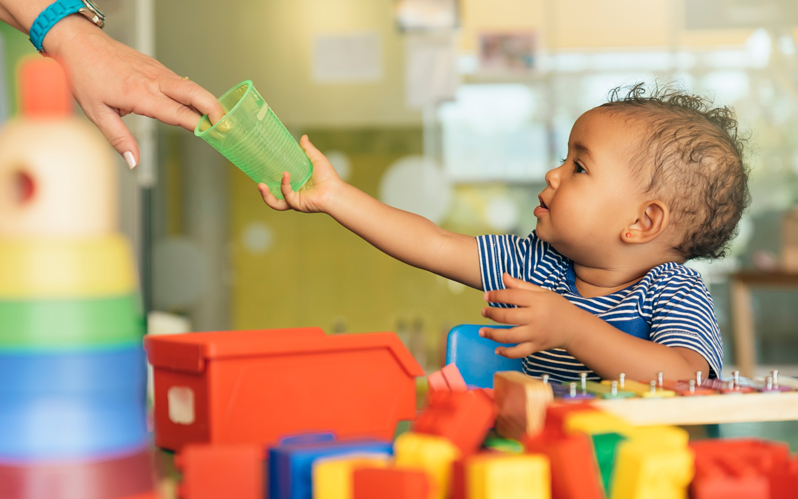 Child grabbing a cup in a daycare setting