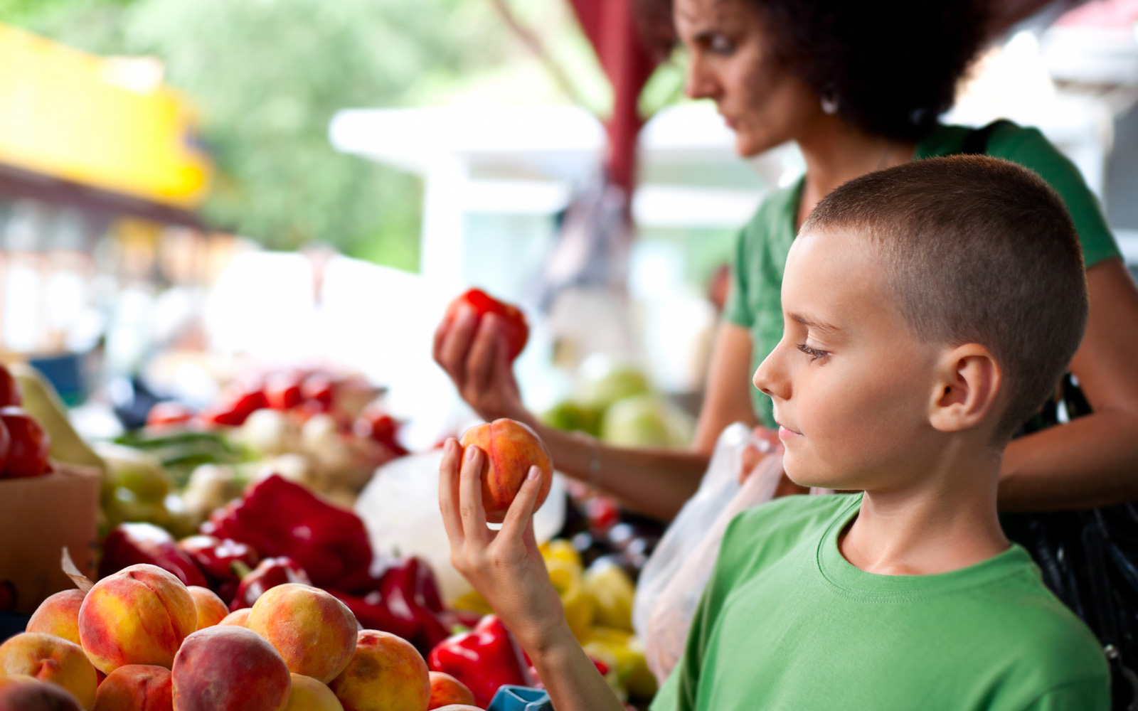 Son and mother pick out fresh fruit at a fall market