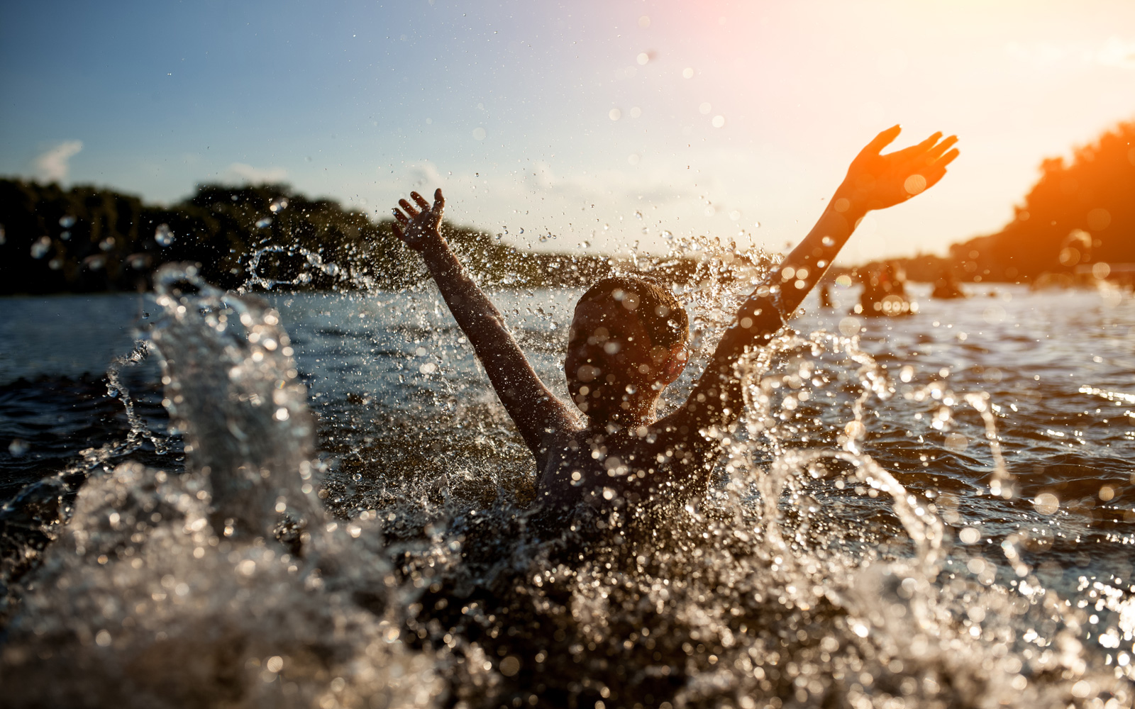 Child playing in a lake at sunrise