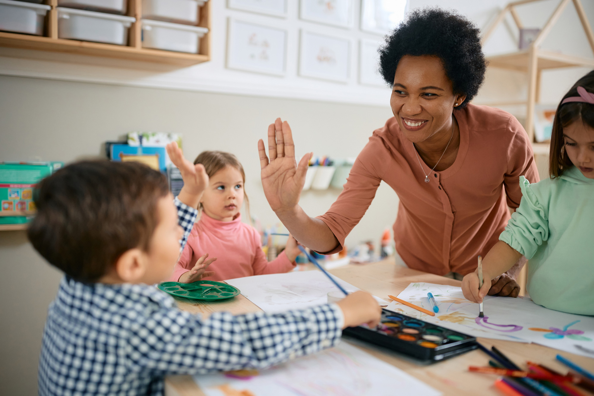 Daycare worker high fives children during class