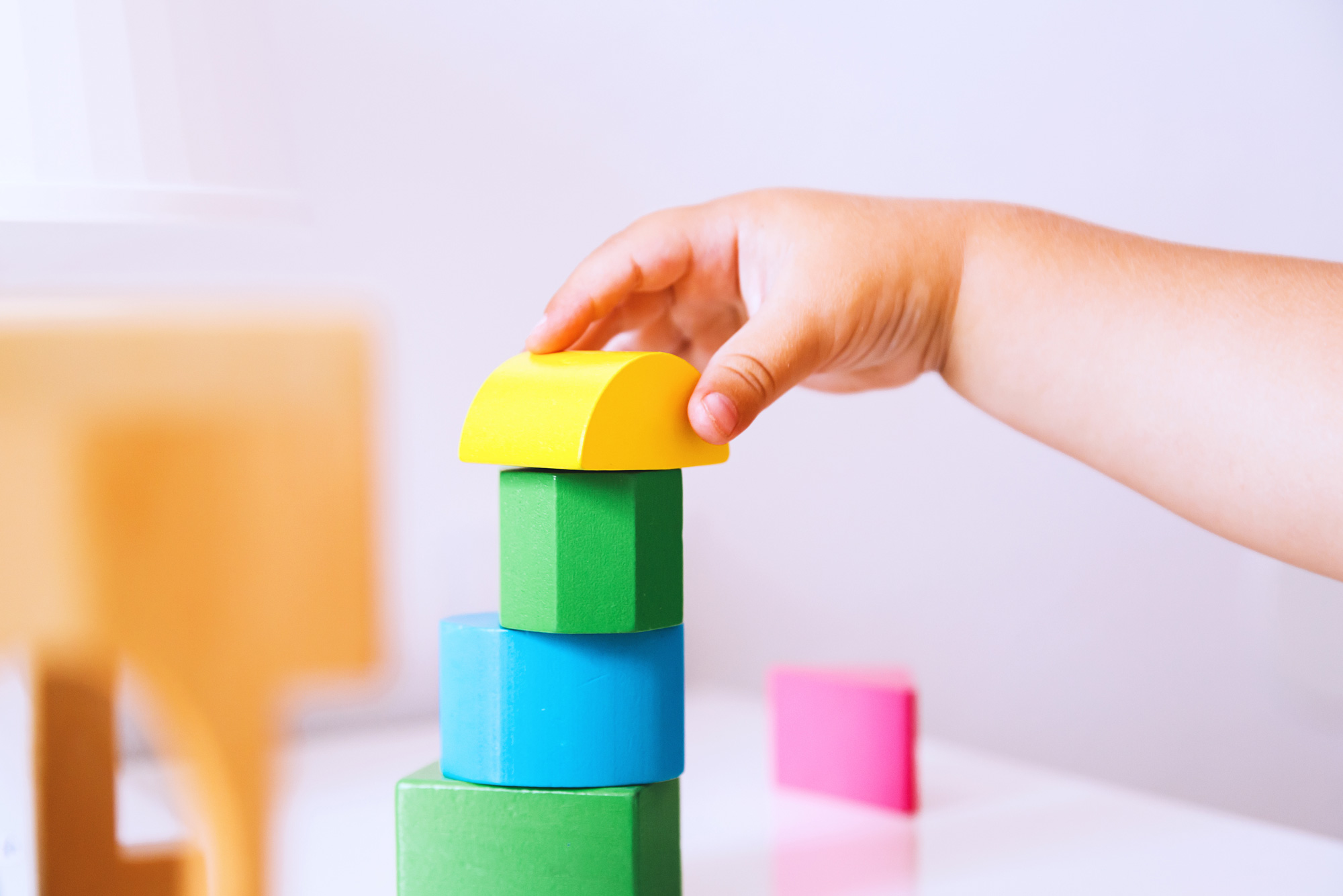 Child's hand stacks colorful blocks