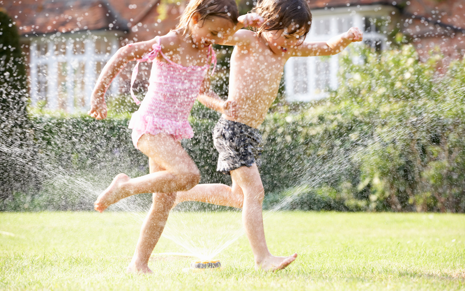 Children run through a sprinkler
