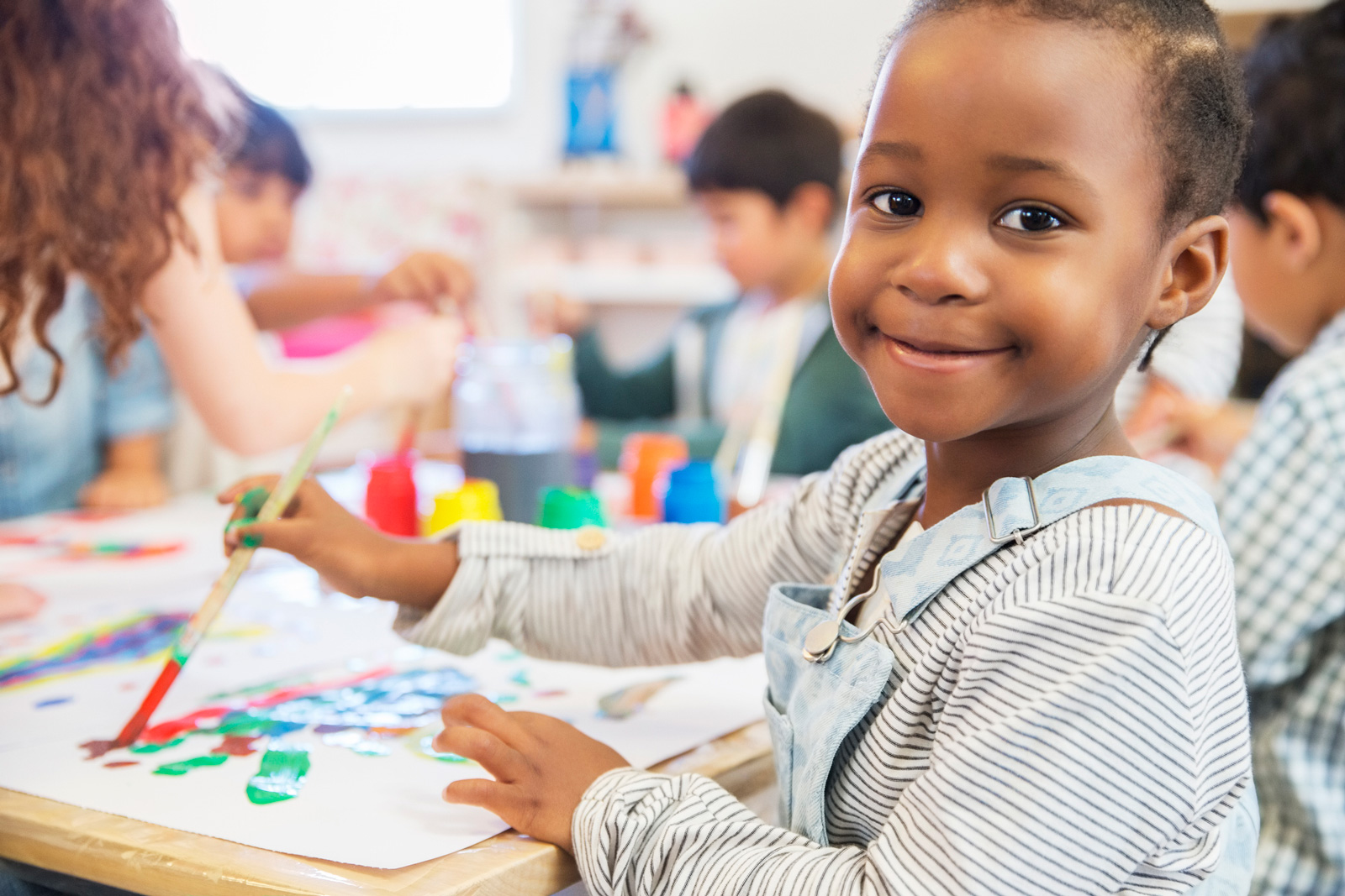 Child smiling while painting in preschool class